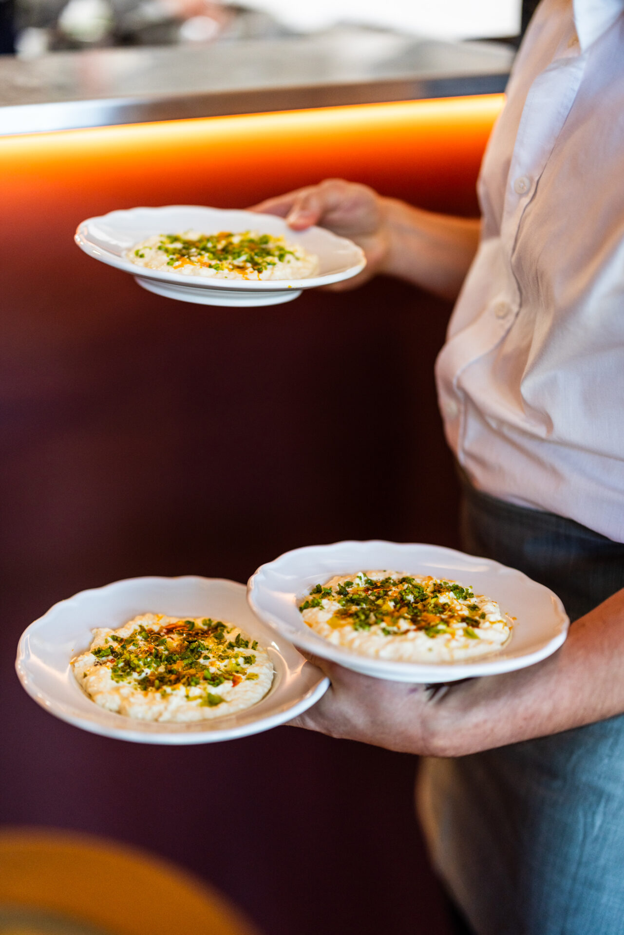 A waiter carrying three plates of food at Bar Vino, Mount Lawley