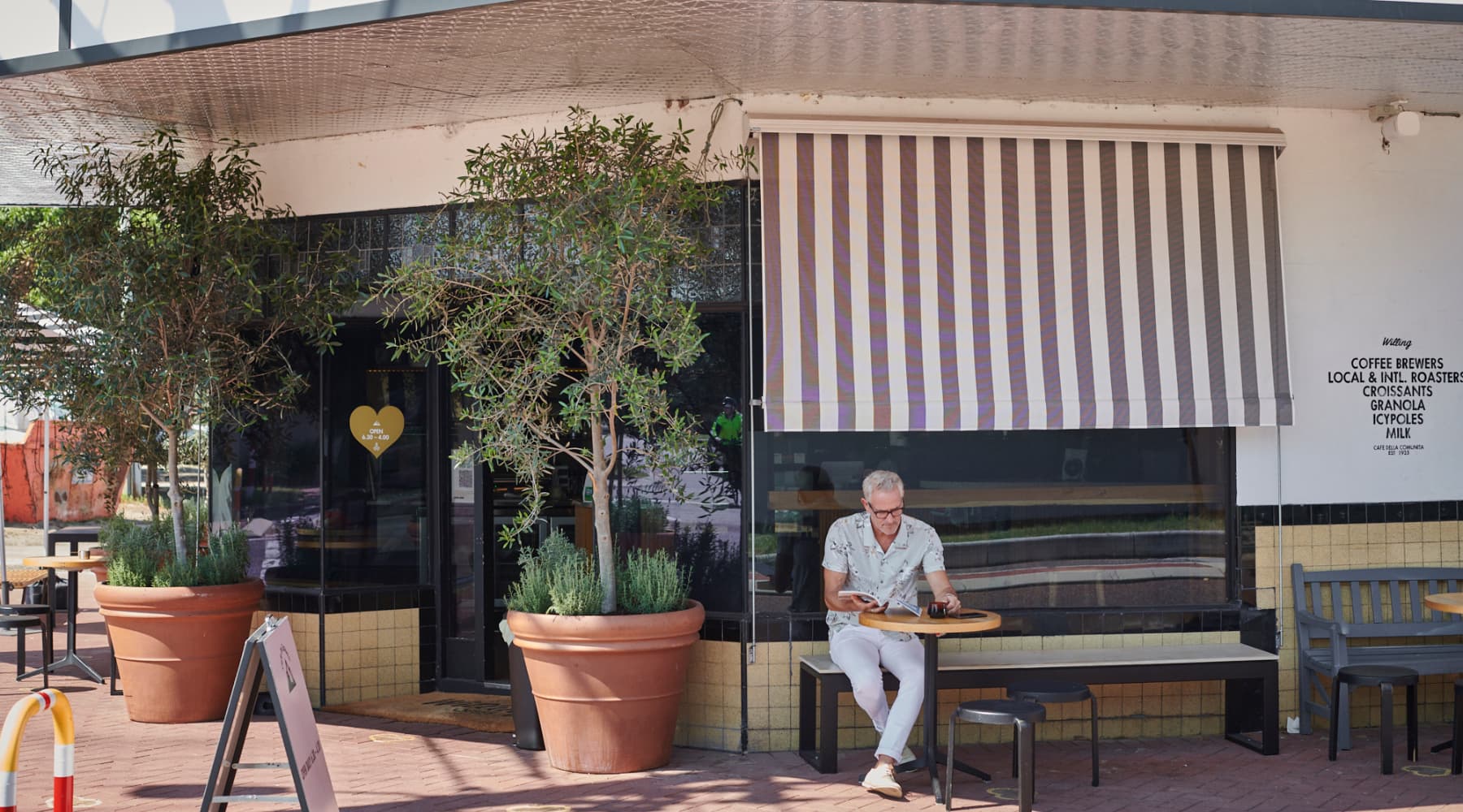 Man reading newspaper outside Willing Coffee in Mount Lawley