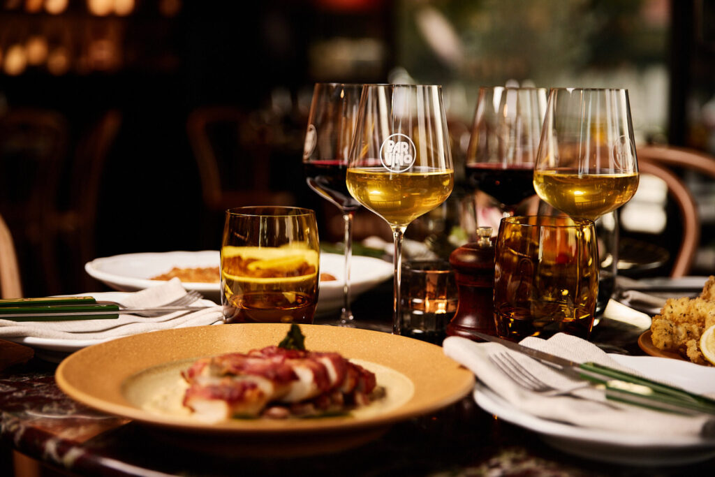 Close up of dining table with food and full wine glasses at Bar Vino Mt Lawley