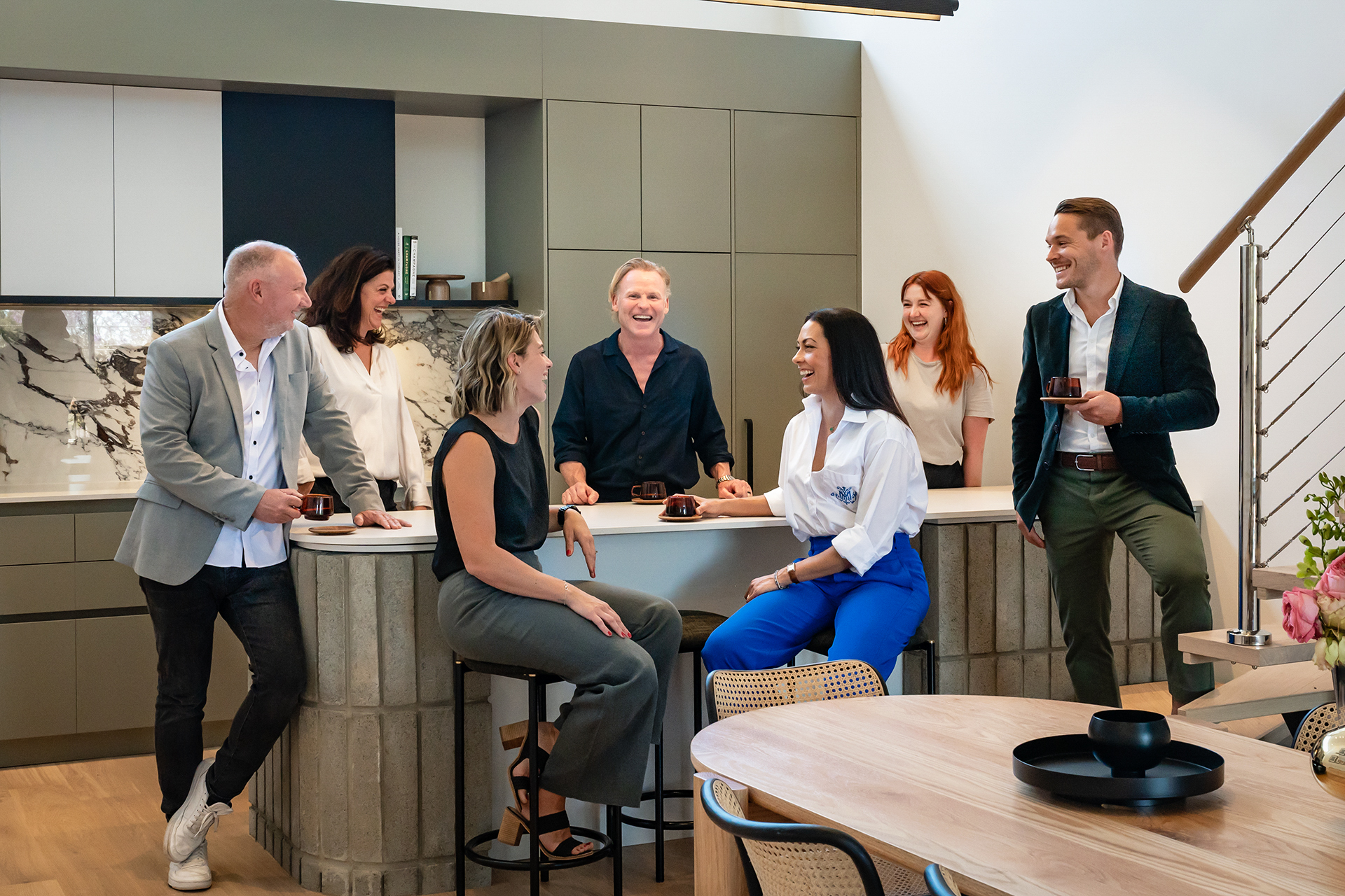 Willing Property team meeting around a kitchen bench laughing and talking