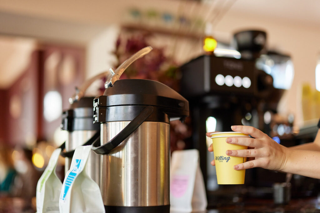 Barista serving coffee in a take-away Bar Vino coffee cup